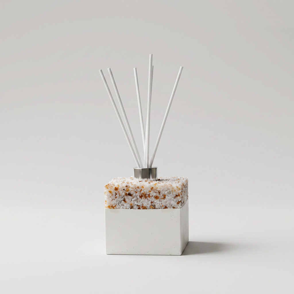 Decorative diffuser with pearl and brown base and white sticks on a light gray background
