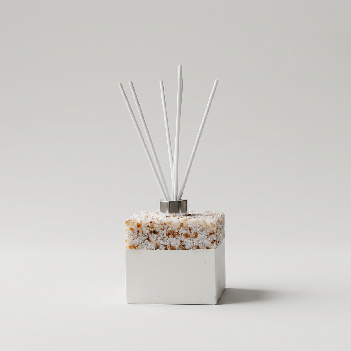 Decorative diffuser with pearl and brown base and white sticks on a light gray background