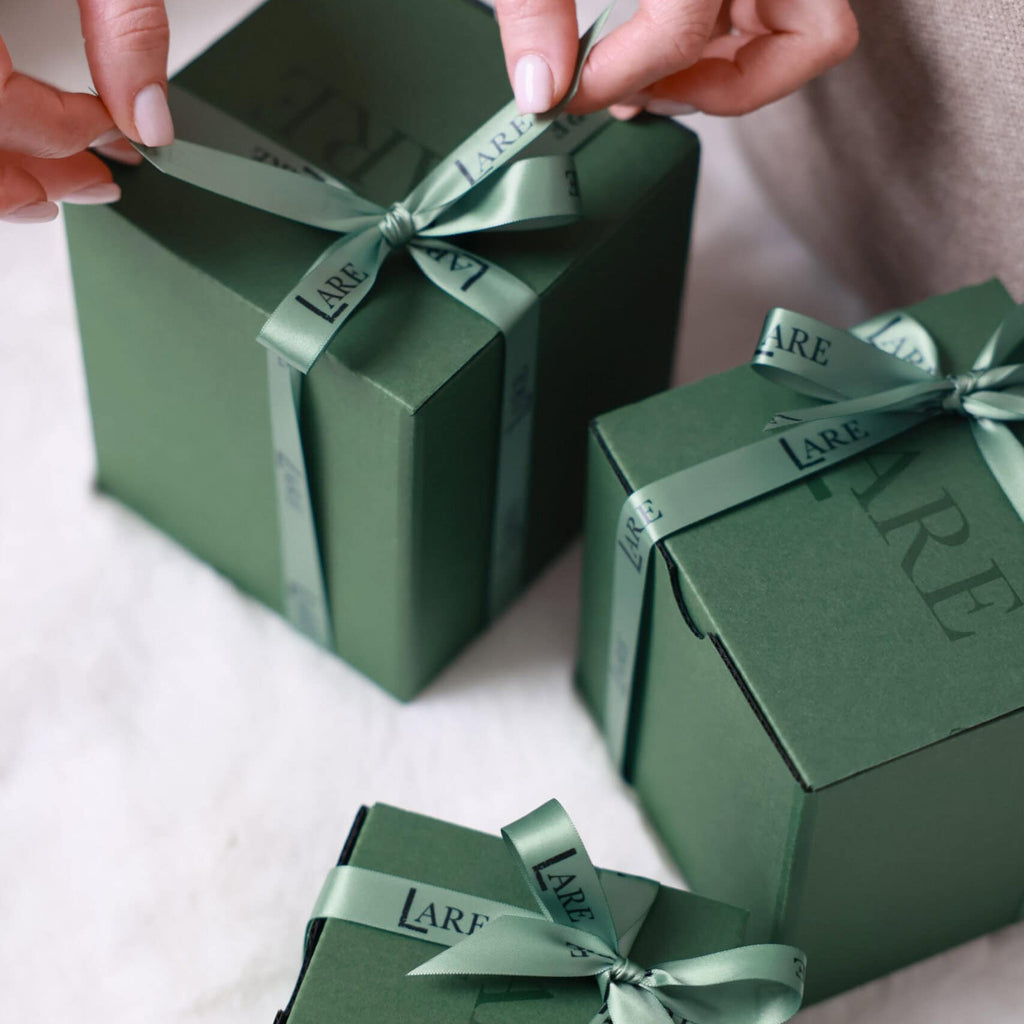 Elegantly wrapped home fragrance gift set in a dark green luxury box with a satin ribbon.