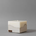 A modern beige candle crafted from high-quality candle natural wax, featured among premium home fragrance products, releasing a luxury scent from candles, on a grey background.