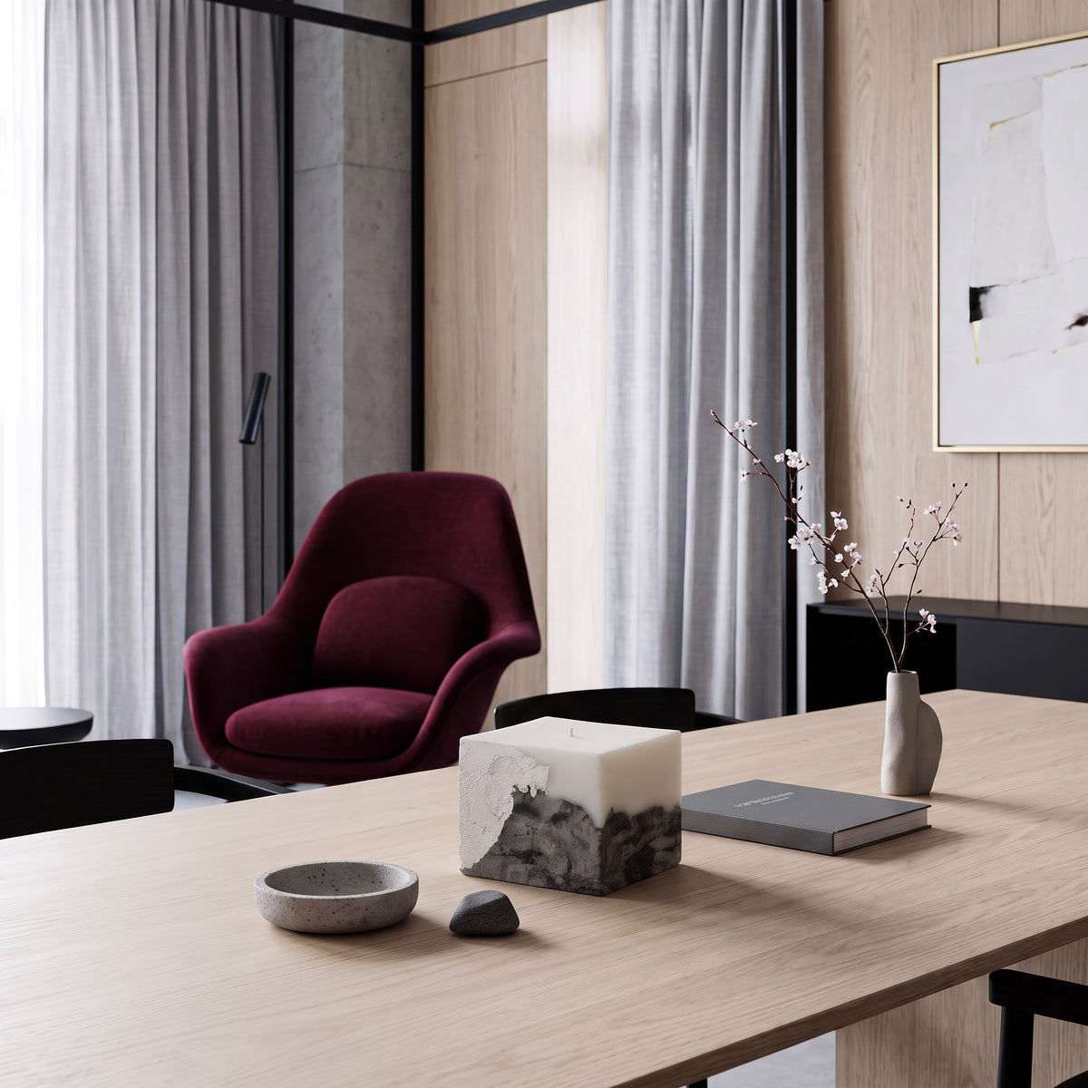 LARE long burning candle on a light wood dining table — sculptural scented soy candle in a modern interior with burgundy armchair.