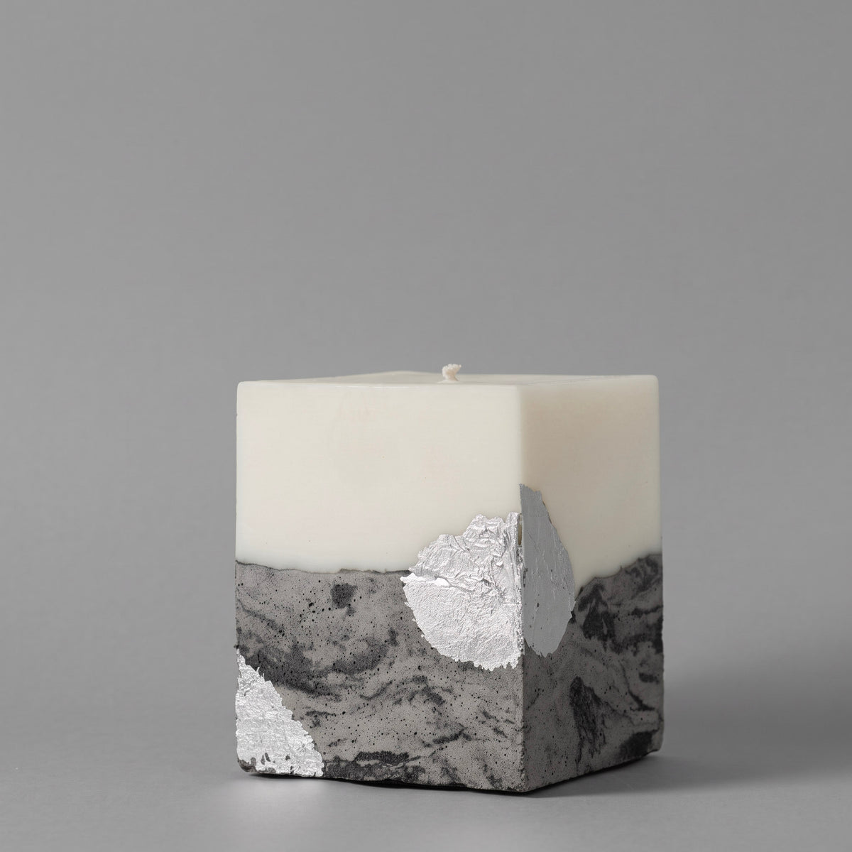 Natural candle by LARE — square sculptural soy wax pillar with marble-patterned concrete base and silver accent.