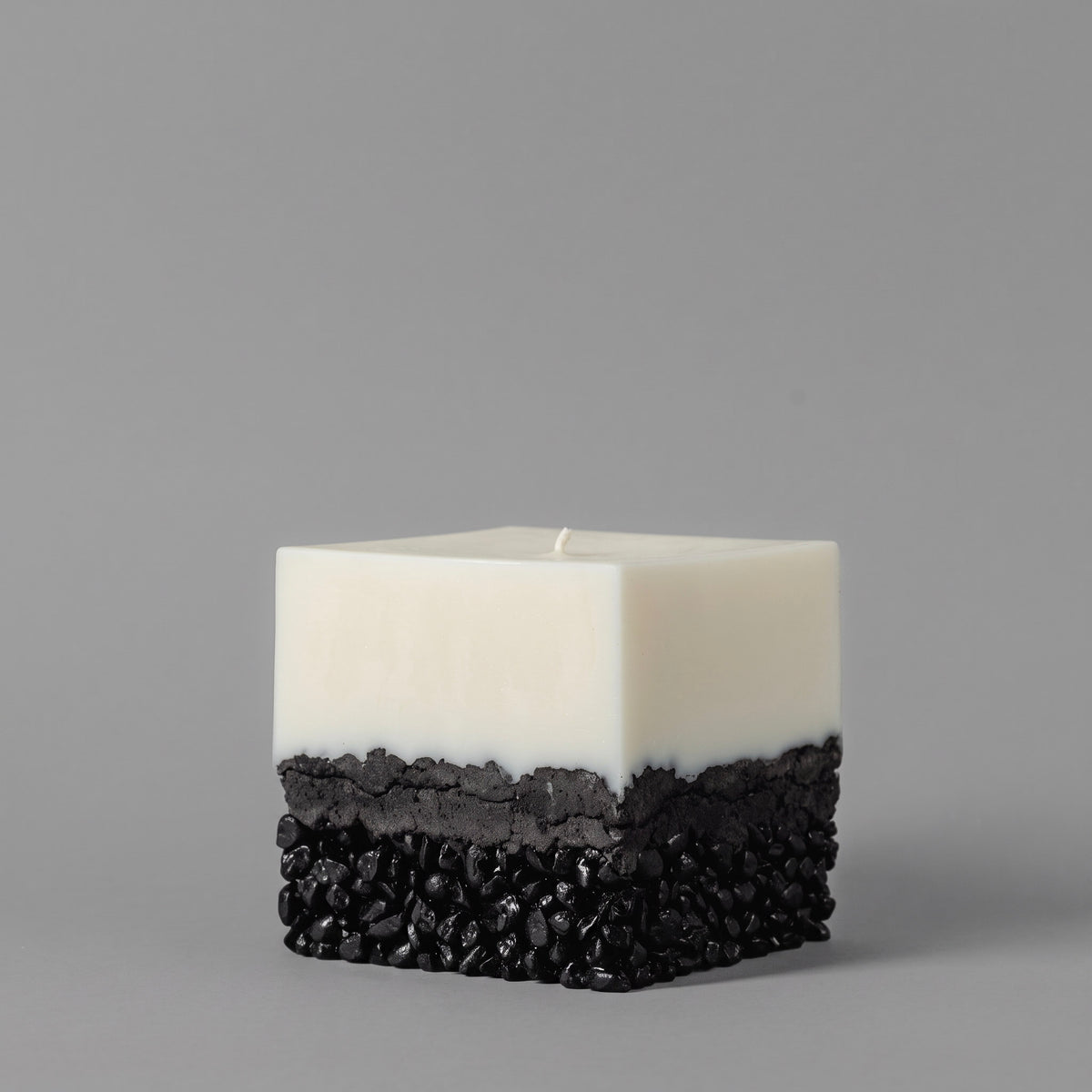 LARE Studio soy candle made with soybean wax for candles, featuring a smooth white top and textured black pebble-effect base on a gray studio background.