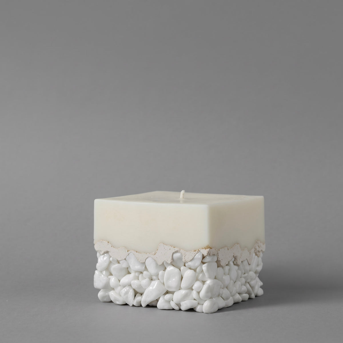 LARE best candles — white sculptural luxury candle with pebble base, unique candles for modern home decor. Photographed against a solid gray studio background.